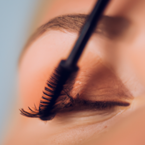 A close-up of a pair of eyes with a brush near the lower lashes.