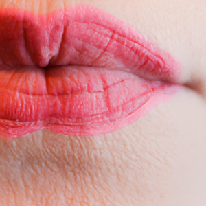  A close-up of a pinkish-red lip with a faint outline of a lip liner.