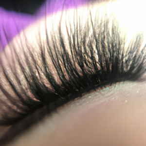 A closeup of a set of eyelashes, with a subtle hint of purple.