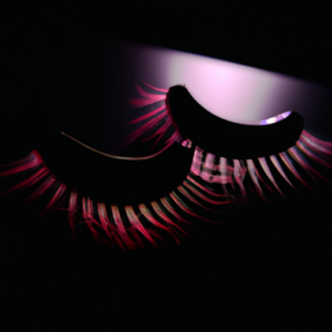 A pair of false eyelashes on a black background with a pink and purple light effect.