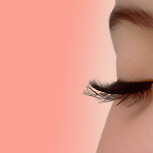 A close-up of thick, luxuriant eyelashes against a soft, pink background.