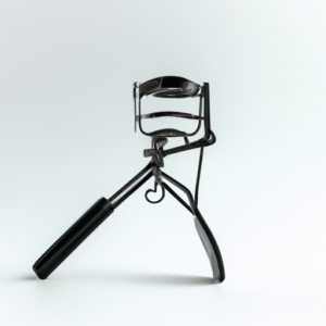 A black eyelash curler against a white background.