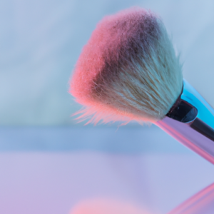 Soft pastel colors with a closeup of a makeup brush on a reflective surface.