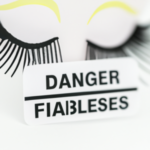 A close-up of a pair of false eyelashes with a warning sign in the background.