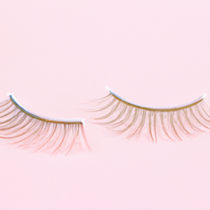 A close-up of a pair of false eyelashes with a soft pink background.