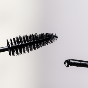 A close-up of a mascara wand with a drop of mascara on the bristles.