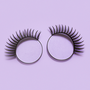 A close-up of a pair of magnetic eyelashes in a circle shape with a light purple background.