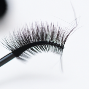 A close-up of a black eyelash brush surrounded by long, lush eyelashes.