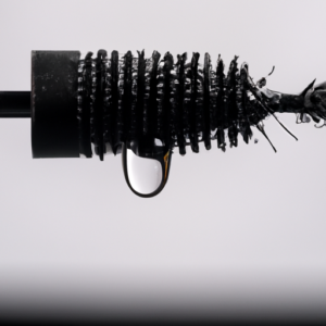 A close-up of a mascara wand dripping with droplets of water.