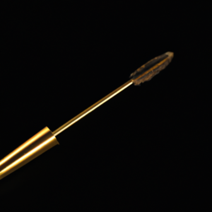 A golden curved mascara wand against a black background.